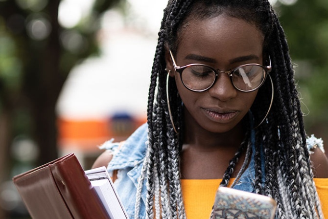 a woman wearing glasses looking at her mobile phone