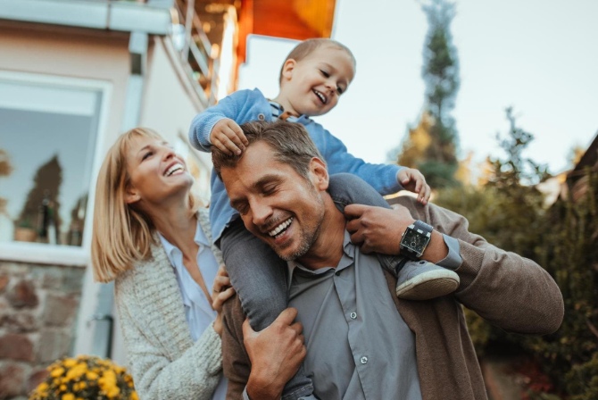 a family of three playing outside their home