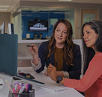 Two ladies working at a computer in an office