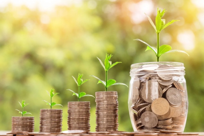 a stack of coins with plants growing from them, next to a jar with coins